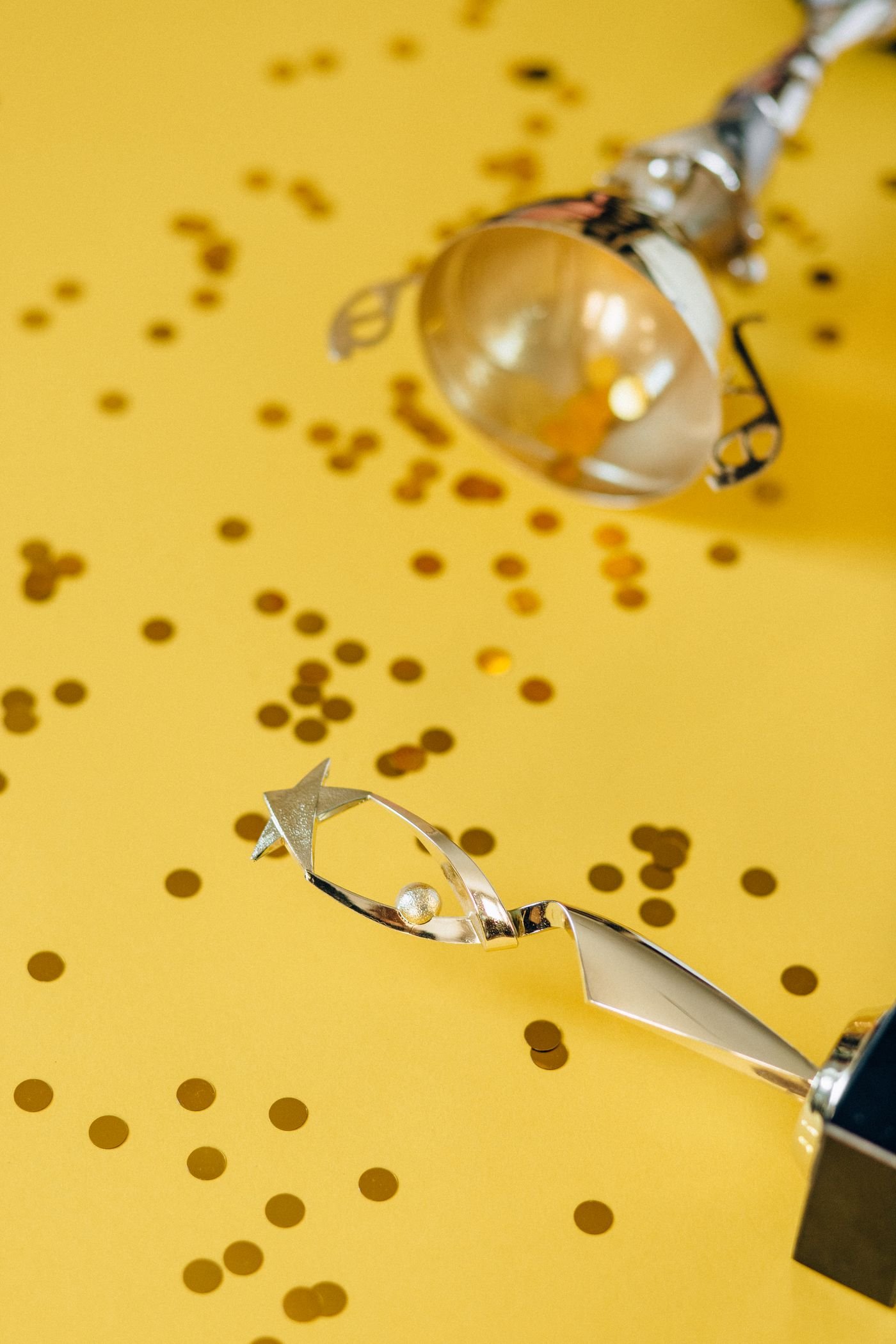 Silver trophies on a yellow background scattered with golden confetti